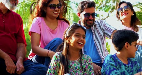 Indian family smiling on steps outdoors spending quality time together on green lawn, cheerful multi-generation portrait of grandparents, parents, and kids bonding, relaxing, enjoying leisure weekend - Powered by Adobe