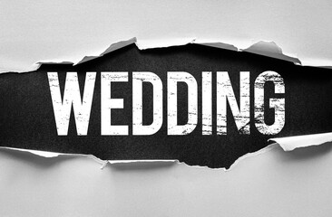 Word WEDDING in bold, distressed white letters revealed beneath torn paper. Conceptual image symbolizing marriage, love, ceremony, union, celebration, event planning, vows, and commitment