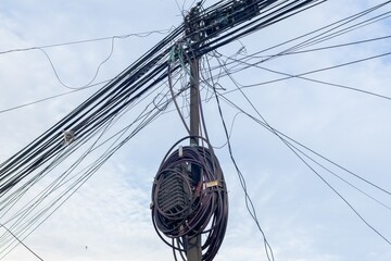 Messy and untidy electrical and internet cables on the electric poles with blue sky background