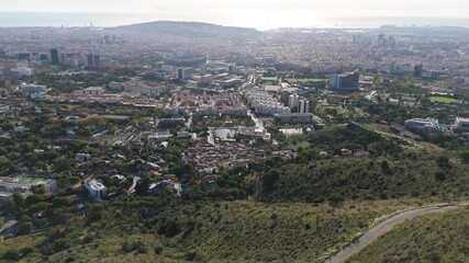 Barcelona cityscape showcasing the diverse urban landscape from an elevated perspective, featuring residential neighborhoods, sports facilities, and the sea under a clear sky