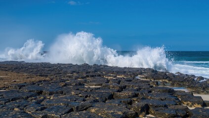 Rocky beach scene with waves crashing against stones, highlighting erosion risk