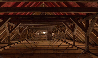 The interior of the attic of an old renovated building. Wooden structural elements and light from a window in the distance are visible. Background.