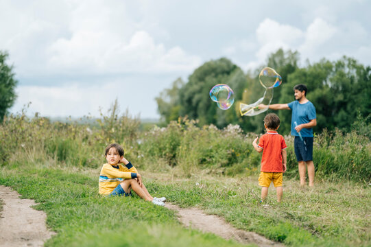 Father playing with soap bubbles and children in field
