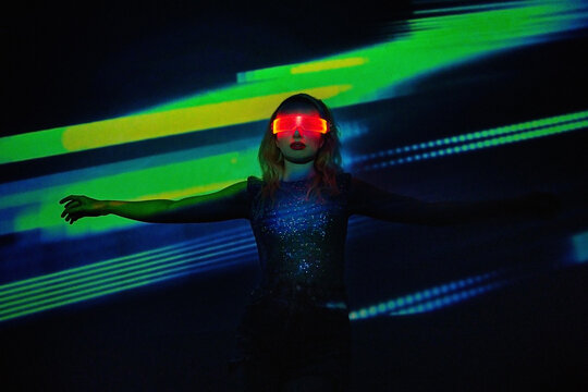 Blond woman wearing VR glasses in futuristic nightclub with neon lights