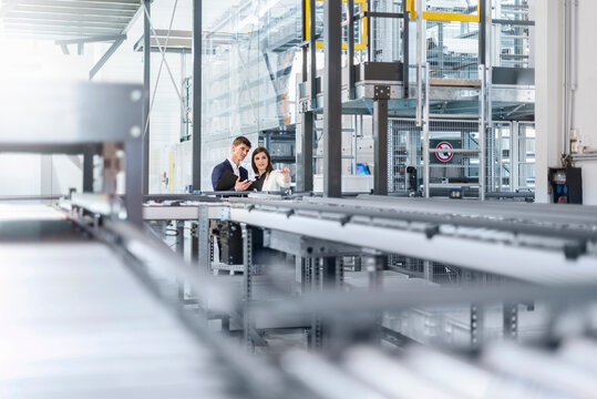 Employees meeting and planning with tablet in modern production hall