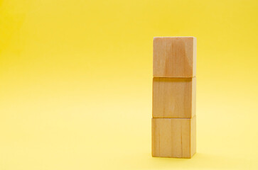 Stake of wooden cubes on yellow background with customizable space for text or ideas. Copy space concept.