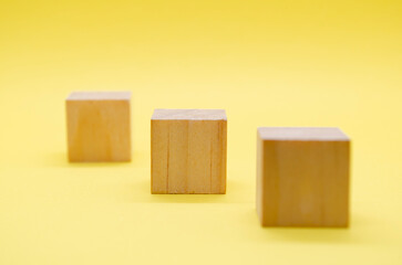 Close up view of isolated wooden cube with customizable space for text or ideas on yellow background.