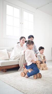 仲良し家族の子育て・育児の日常　リビングでの子供のお世話全身　見守る夫婦の縦動画