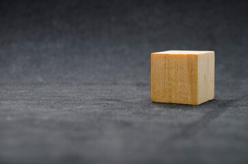 An isolated wooden cube on dark background with customizable space for text or ideas. Copy space concept.