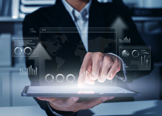 Fototapeta premium Businessman Analyzing Business Data Charts and Global World Map on Digital Tablet Screen, Showing Financial Information Management, Corporate Strategic Planning, and Data Visualization Dashboard.