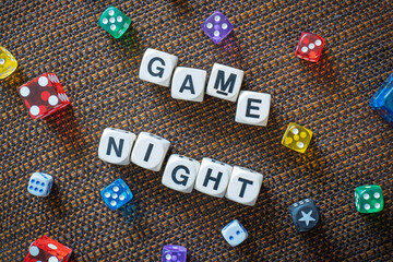 GAME NIGHT spelt using wooden word dice with vibrant set over a brown table cloth background - perfect for promoting game events or fun family gatherings.