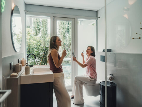 Sisters having fun and getting ready together in a bathroom at home