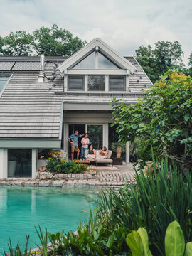Family relaxing by pool at modern villa with garden in summer