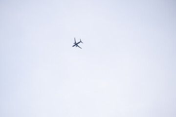 Airplane silhouette flying high in cloudy sky