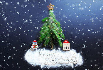 Christmas tree made of fir branches with a star topper, standing over white "Merry Christmas" text and figures, with falling snow