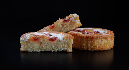 Beautiful sponge cakes whole and cut on a black background.