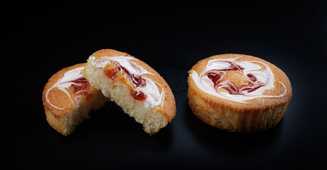Beautiful sponge cakes whole and cut on a black background.