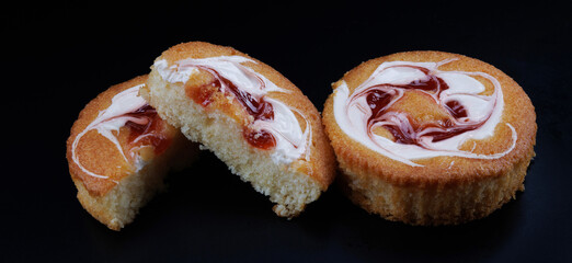 Beautiful sponge cakes whole and cut on a black background.