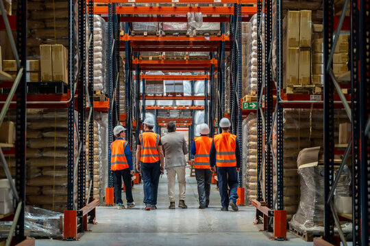 Logistics team and manager walking through warehouse aisle - Powered by Adobe