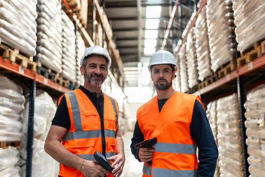 Warehouse workers holding scanners checking inventory and collaborating
