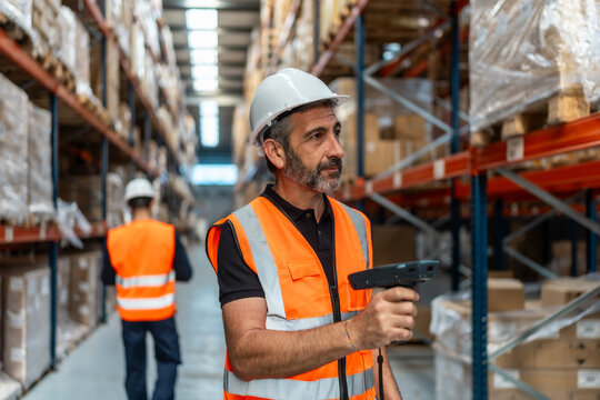 Warehouse worker wearing safety vest scanning parcel - Powered by Adobe