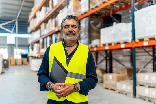 Warehouse worker standing inspecting inventory and supply chain operations