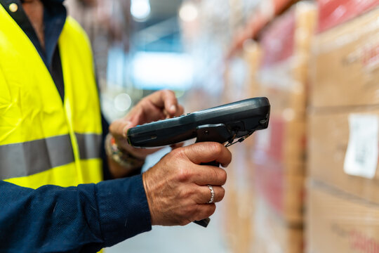 Warehouse worker scanning barcode on cardboard box controlling inventory - Powered by Adobe