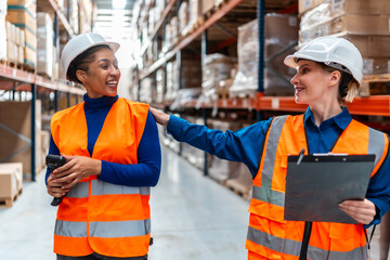 Logistics workers collaborating in modern warehouse looking happy