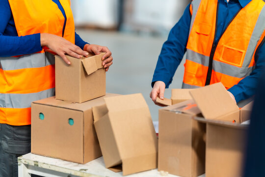 Warehouse workers packing cardboard boxes for shipping logistics