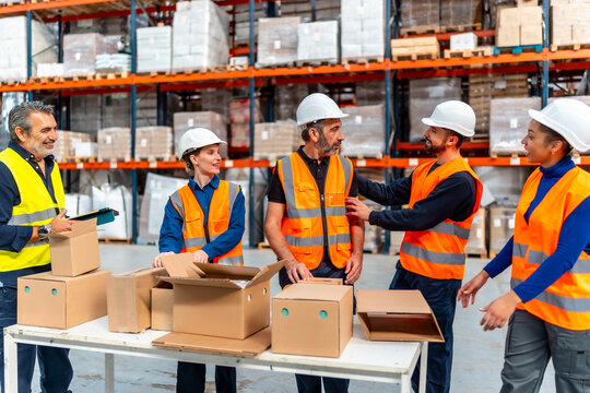 Diverse logistics workers collaborating packaging goods in warehouse