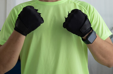 Close up of an unrecognizable man wearing sports gloves clenching his fists. Concept of strength, energy, motivation, and readiness for training