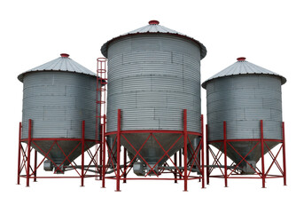 Isolated metal grain bins storing grain on a farm, red support structures, ladders, silver color