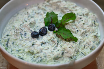 Tzatziki Sauce. Three blueberries and small green leaves are decoratively placed on top