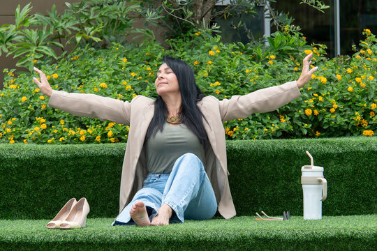 Mulher relaxando descal&ccedil;a em &aacute;rea verde urbana, descanso, pausa no trabalho, bem-estar, lifestyle, natureza, casual, equil&iacute;brio vida profissional e pessoal, sa&uacute;de mental, ver&atilde;o, tranquilidade