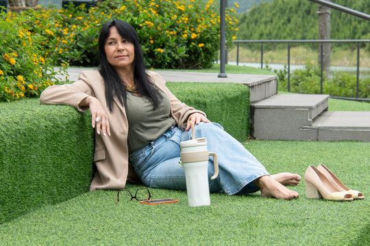 Mulher relaxando descal&ccedil;a em &aacute;rea verde urbana, descanso, pausa no trabalho, bem-estar, lifestyle, natureza, casual, equil&iacute;brio vida profissional e pessoal, sa&uacute;de mental, ver&atilde;o, tranquilidade