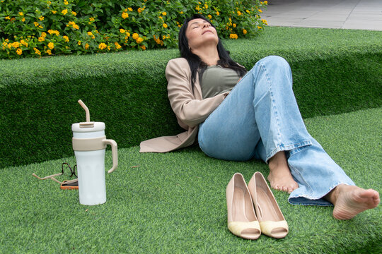 Mulher relaxando descal&ccedil;a em &aacute;rea verde urbana, descanso, pausa no trabalho, bem-estar, lifestyle, natureza, casual, equil&iacute;brio vida profissional e pessoal, sa&uacute;de mental, ver&atilde;o, tranquilidade