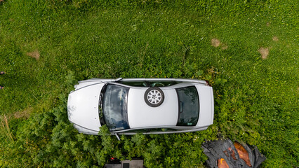 Abandoned car surrounded by dense green grass and plants in a rural area