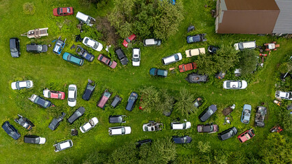 Abandoned cars scattered across a grassy field in a rural area during daytime