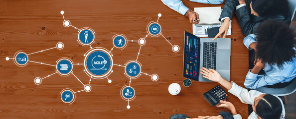 A top-down view of a professional team collaborating on agile projects. They use technology and teamwork to brainstorm ideas, analyze data, and strategize for success. Amity