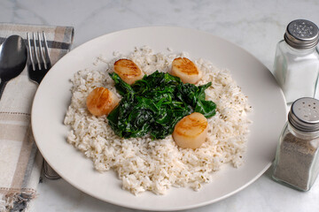 rice top with spinach and scallops