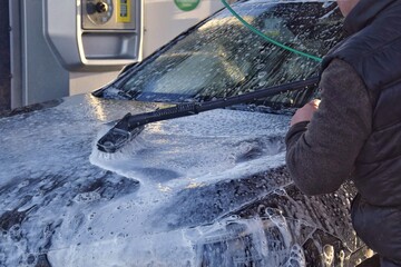 A man washing a car at a self-service car wash.