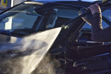 A man washes his car at a self-service station.