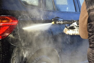 A man washes his car at a self-service station.
