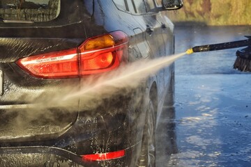 A man washes his car at a self-service station.