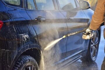 A man washes his car at a self-service station.