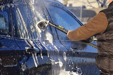 A man washing a car at a self-service car wash.