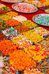 plates of colorful chewy candies on red tablecloth at a fair in vietnam