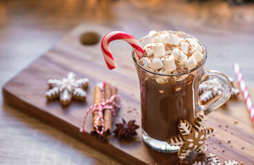 Cup of hot chocolate with marshmallow and candy cane in front of Christmas tree