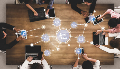 A dynamic business meeting scene showcasing a diverse team engaged in collaboration around a wooden table, utilizing technology and data visualization for productive discussions. Tessel