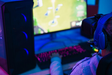 Gamer playing at strategy pc game online using vr ai headset - Gaming and young people generation lifestyle concept - Focus on headphones © DisobeyArt